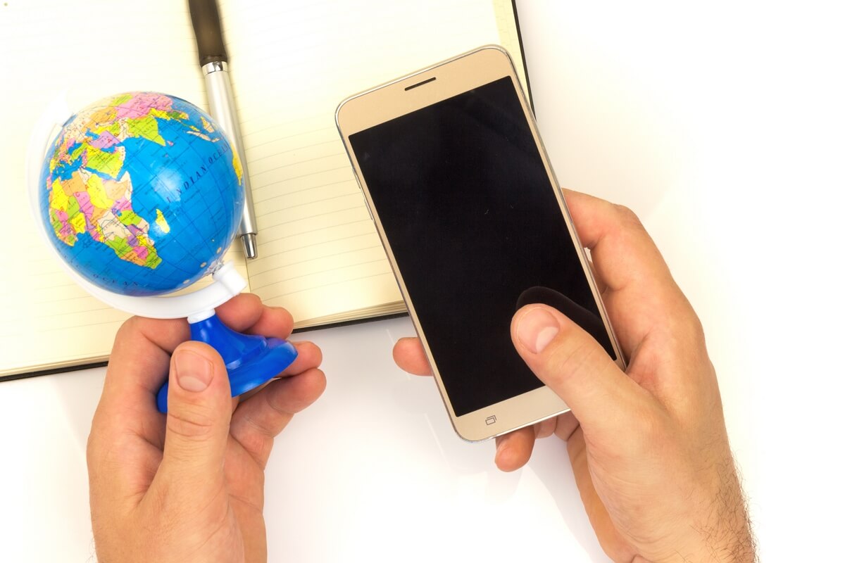 Mappemonde et smartphone dans la main, car Sosh a un super forfait spécial pour l'Afrique