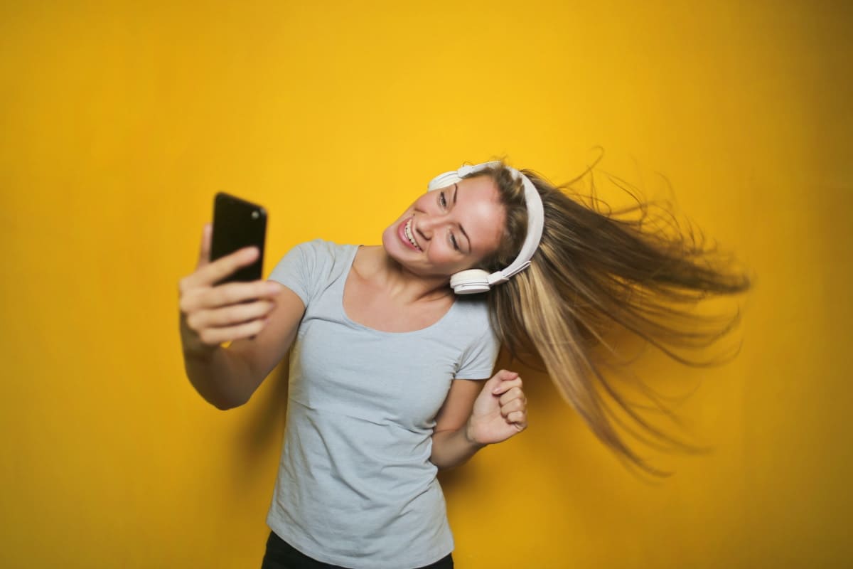 Fille avec écouteurs et smartphone écoute de la musique avec son Galaxy A15, en super promo chez Amazon