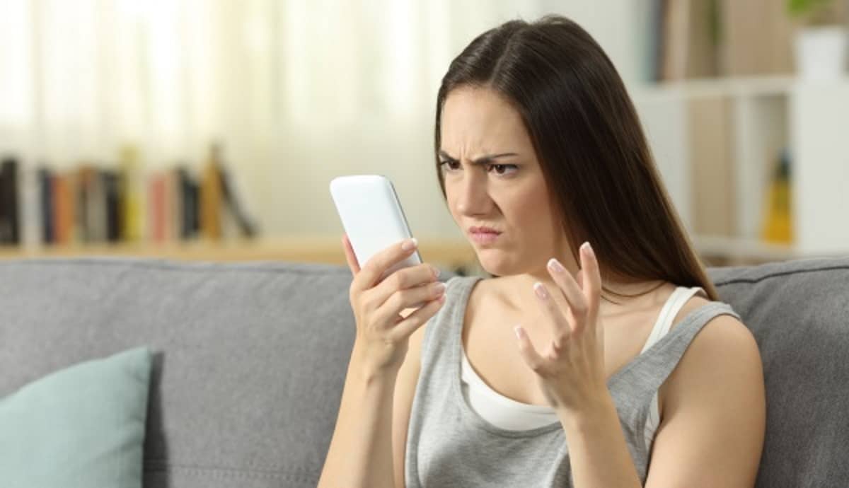 Femme fait la moue en regardant son smartphone, car elle va perdre sa connexion 2G