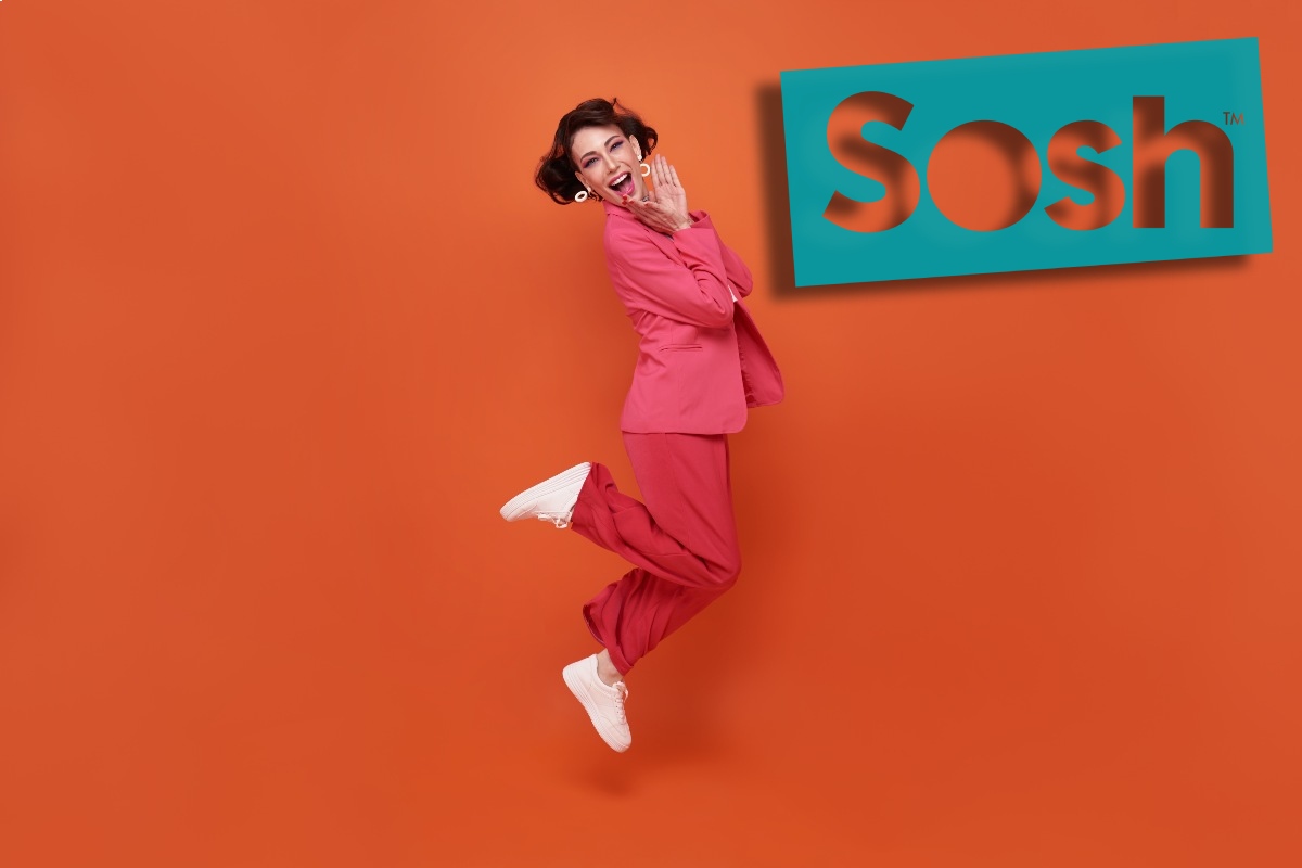 Femme en tailleur rose saute de joie sous le logo de Sosh, qui lance une nouvelle promo pour acheter un smartphone à moindre coût