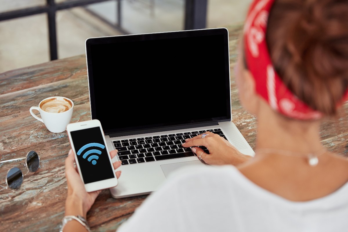 Femme dans son canapé avec PC portable, sourit car elle navigue sans Box Internet