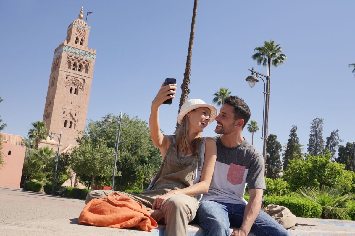 Un homme et une femme téléphonant place Jamaa El Fna au Maroc grâce à leur forfait "voyage" chez Syma Mobile, Sosh ou B&YOU