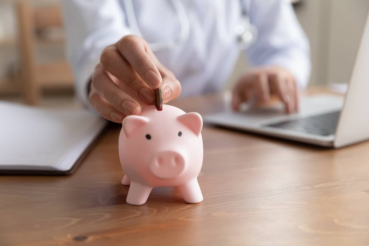 Homme derrière ordinateur met pièce dans cochon tirelire ose grâce aux économies réalisées avec la Box de RED by SFR