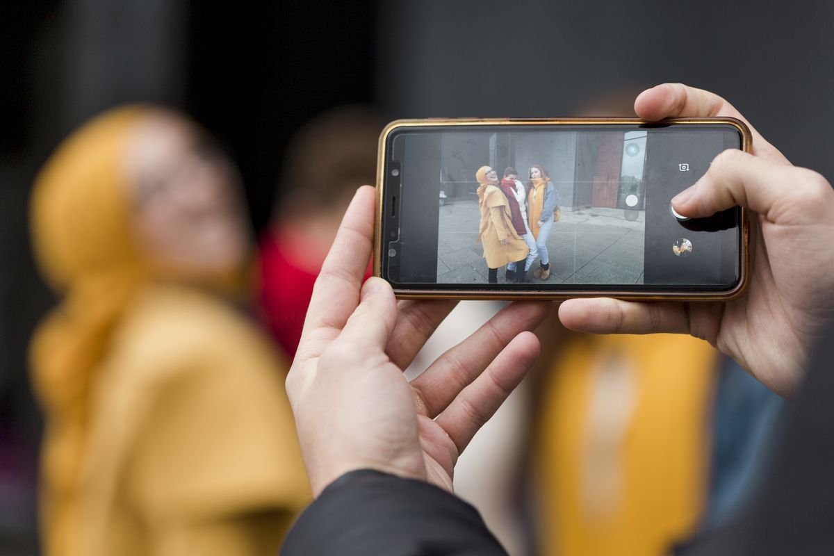 Un homme prend en photo des amies sur son smartphone