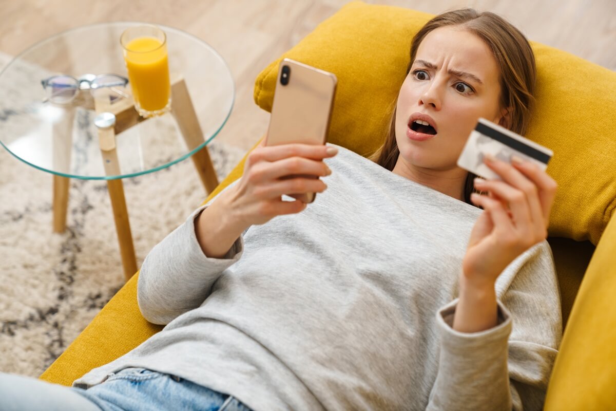 Femme sur canapé avec smartphone et carte bancaire, surprise de trouver 100 Go à moins de 8€ chez YouPrice avec "Le Néo"
