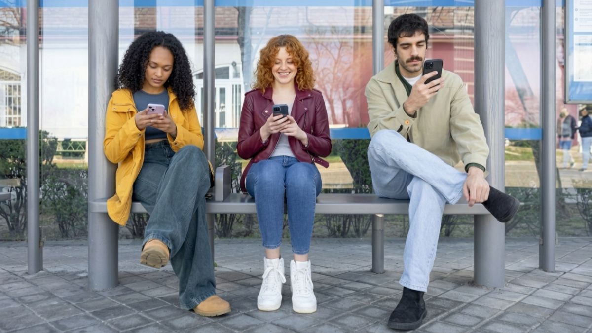 3 personnes attendent le bus en regardant leur smartphone