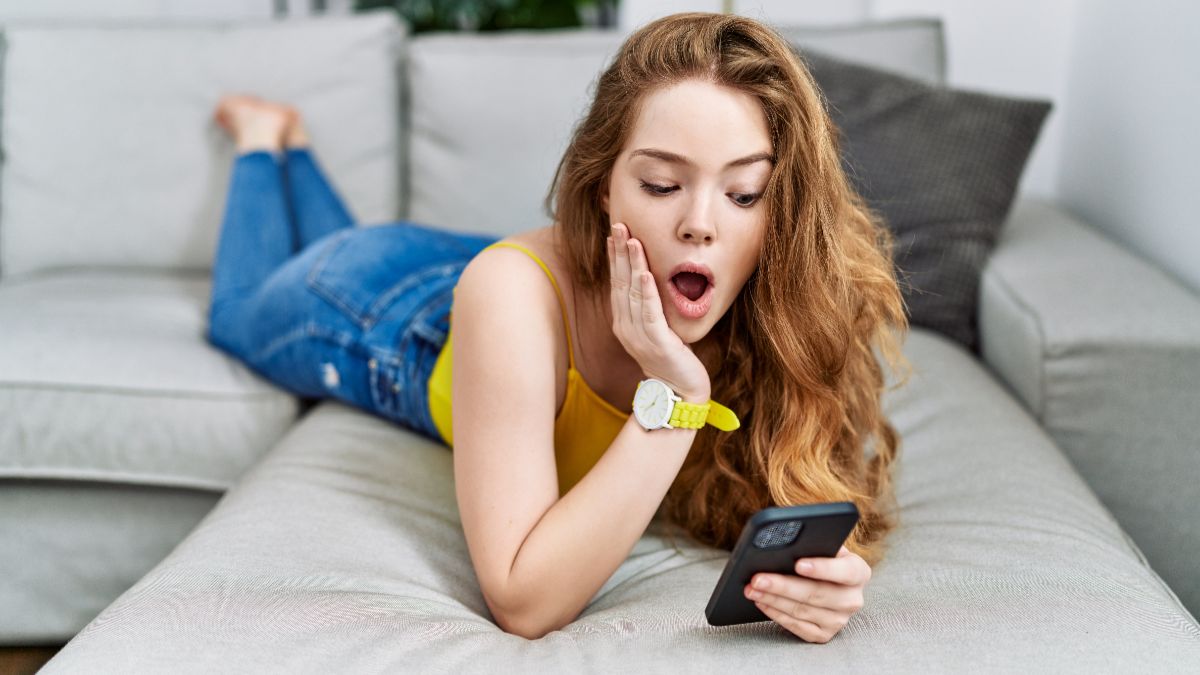 Femme allongée sur canapé regarde son smartphone, bouche ronde d'effroi et surprise devant les 300Go en 5G à moins de 12€ chez Lebara
