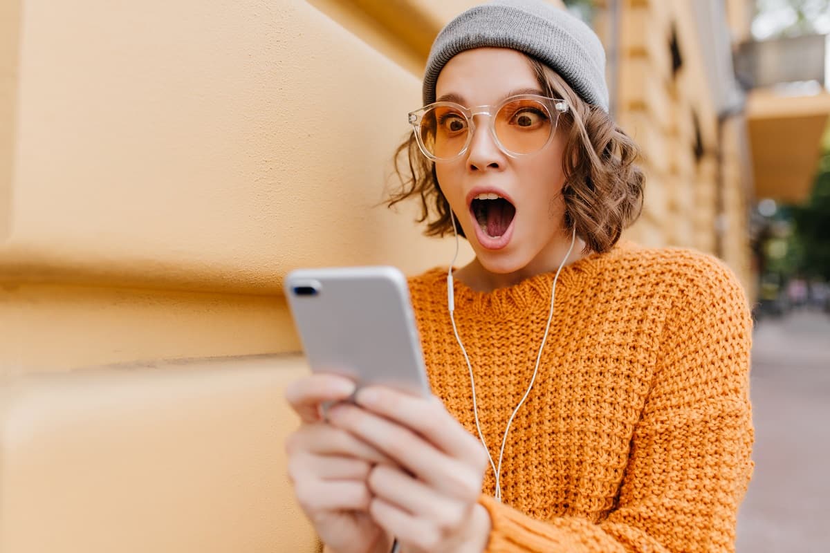 Femme à bonnet gris et pull orange, bouche bée devant les tarifs des forfaits de Coriolis