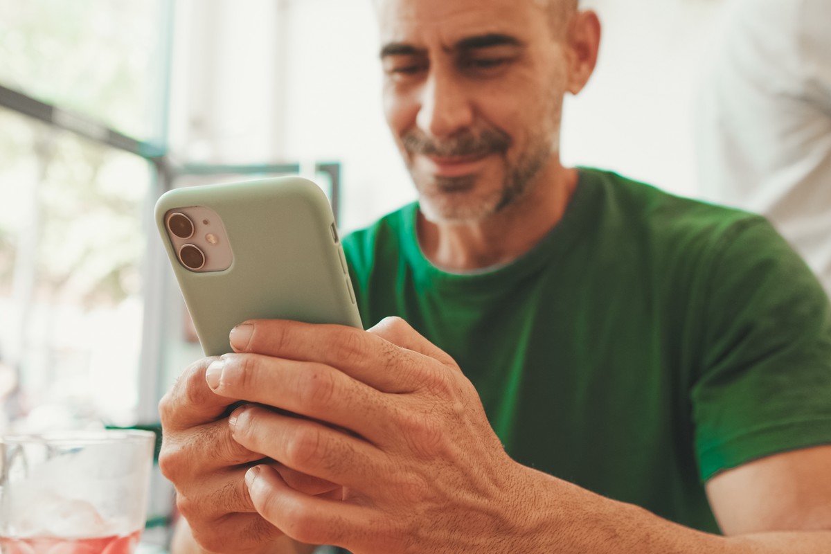 Un homme regarde des vidéos en streaming sur son smartphone vert