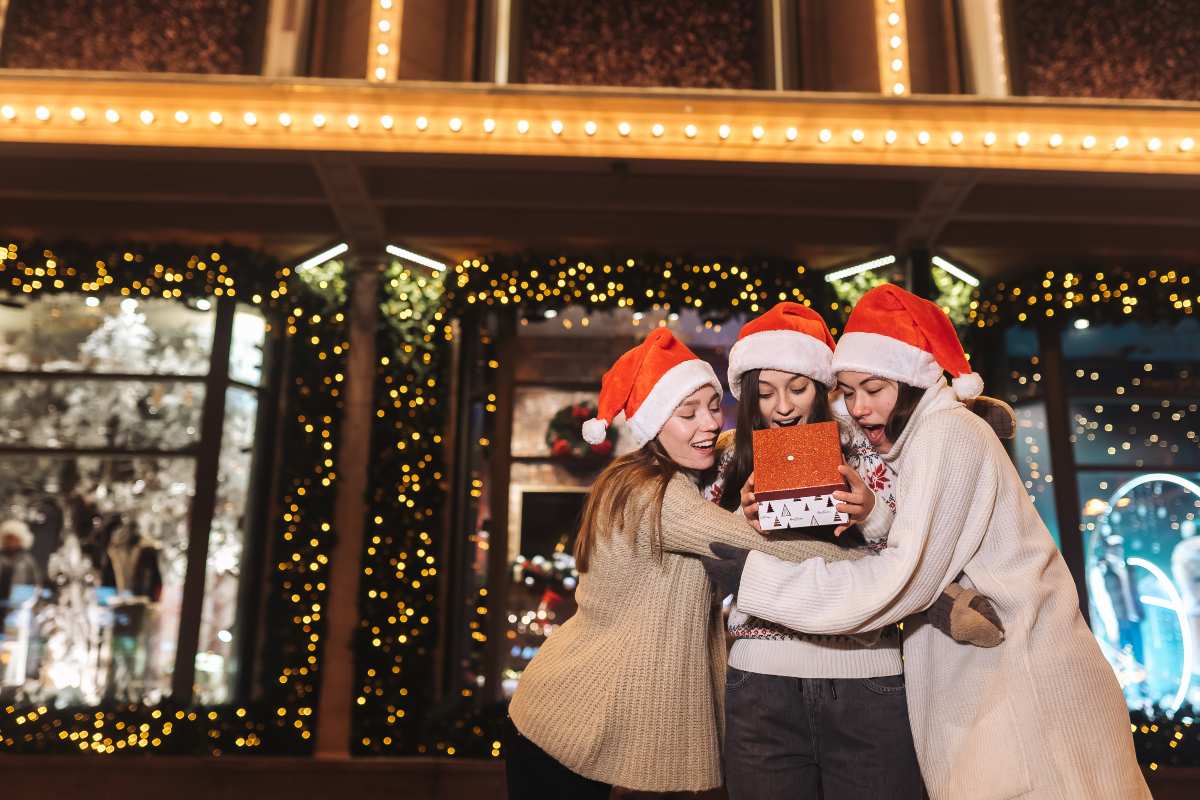 3 Filles avec bonnet de Père Noël ouvrent un cadeau dans la rue, ravies de découvrir 80 Go à 6.99€ et 4 mois de Deezer gratuit grâce à RED by SFR