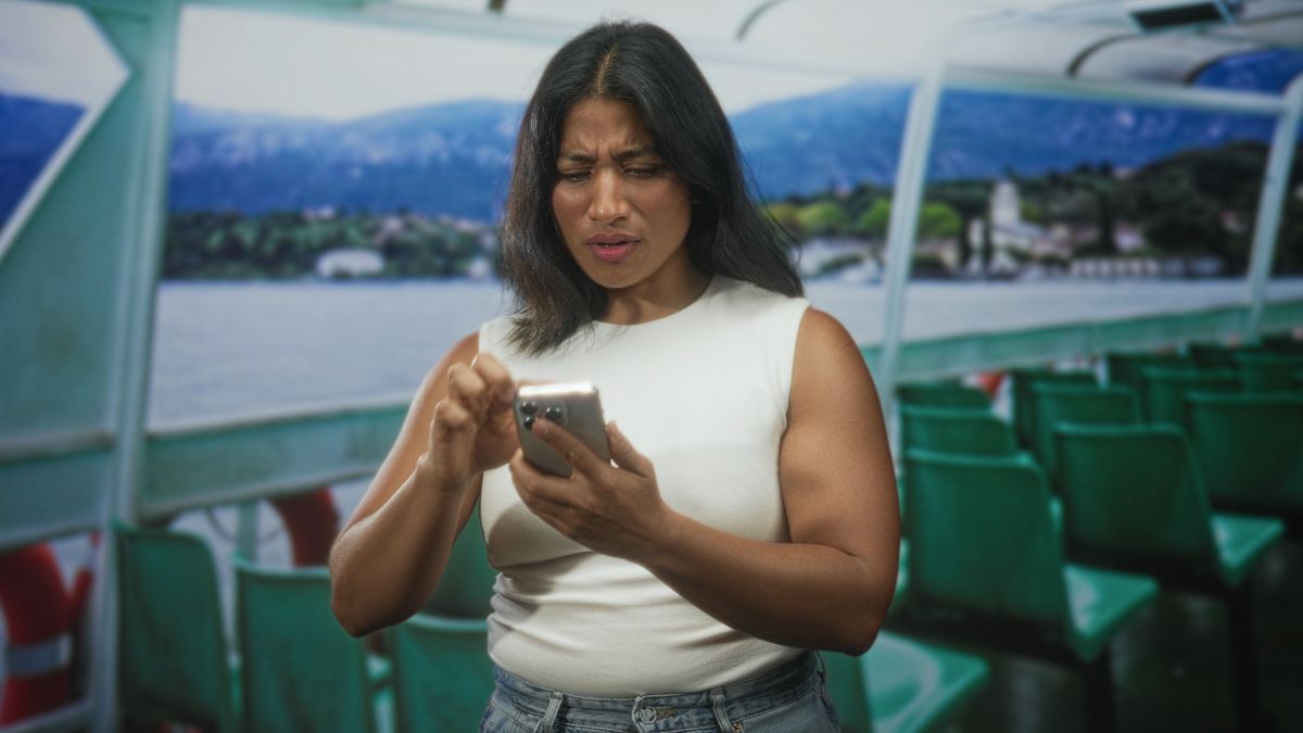 Femme sur un ferry, pas contente en regardant son smartphone car hors forfait couteux