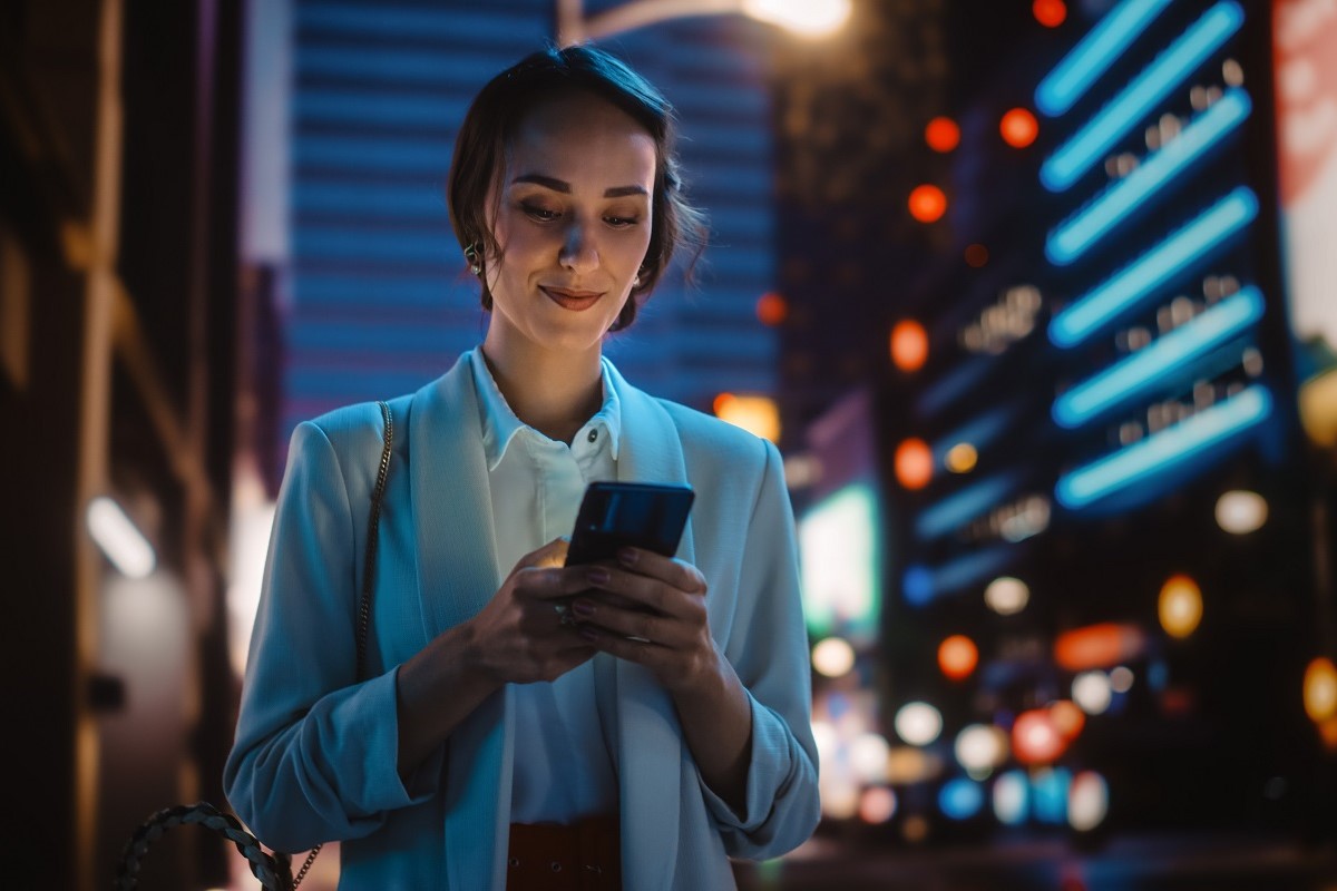 Une femme surfe sur son smartphone dans une grande métropole la nuit