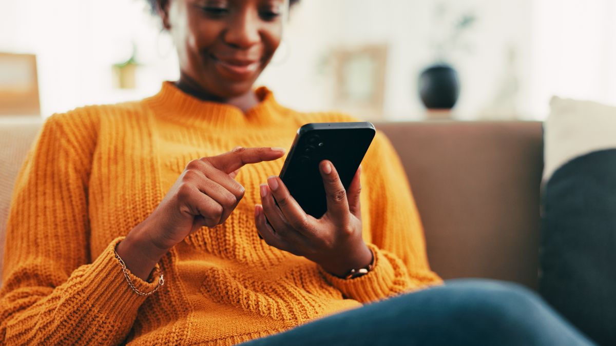 Homme scrolle sur son smartphone en souriant, ravi de l'application Cafeyn offerte pour 6 mois avec son forfait mobile de Bouygues Telecom