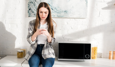 Une jeune femme capte mal le Wi-Fi près de son four micro-ondes