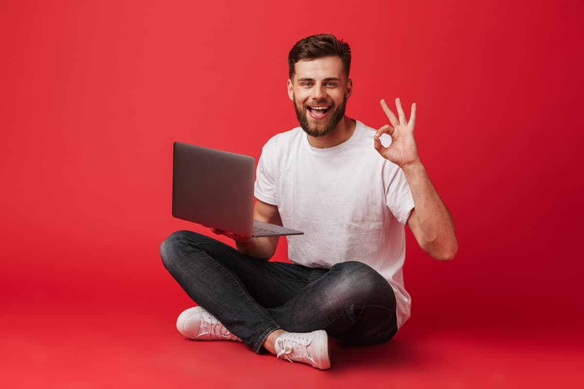 Homme assis avec PC fait signe que tout va bien avec sa main, car sa résiliation Box s'est bien passée