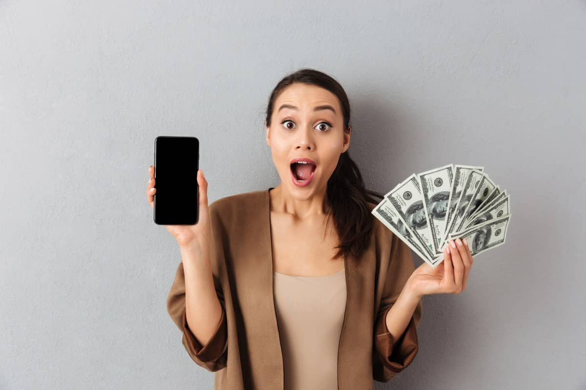 Femme avec liasse de billet et smartphone à 1€ de Bouygues Telecom