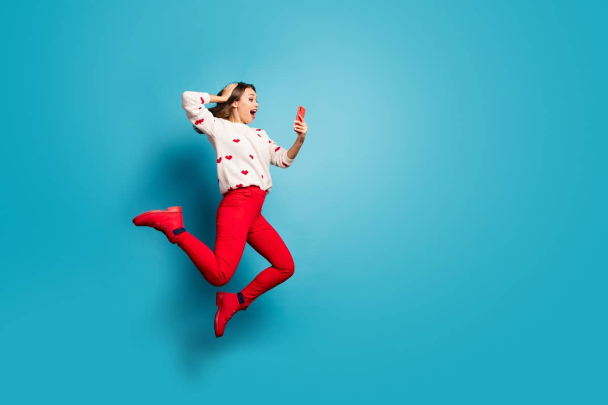 Fille sur fond bleu saute de joie car son forfait est sans engagement