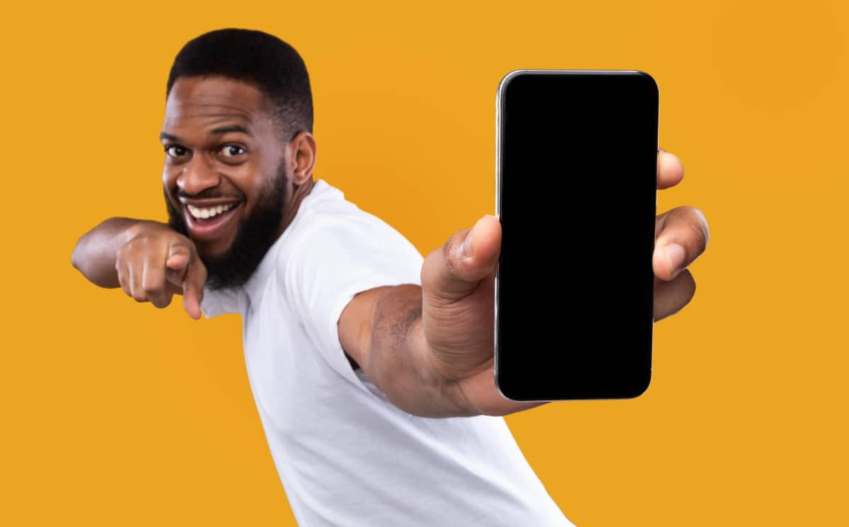 Homme content montre son smartphone avec forfait de 30 Go à moins de 7€ chez 4 opérateurs low-cost