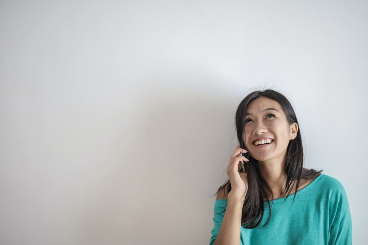 Femme au téléphone sourit car appels de qualité en VoLTE ou WiFi