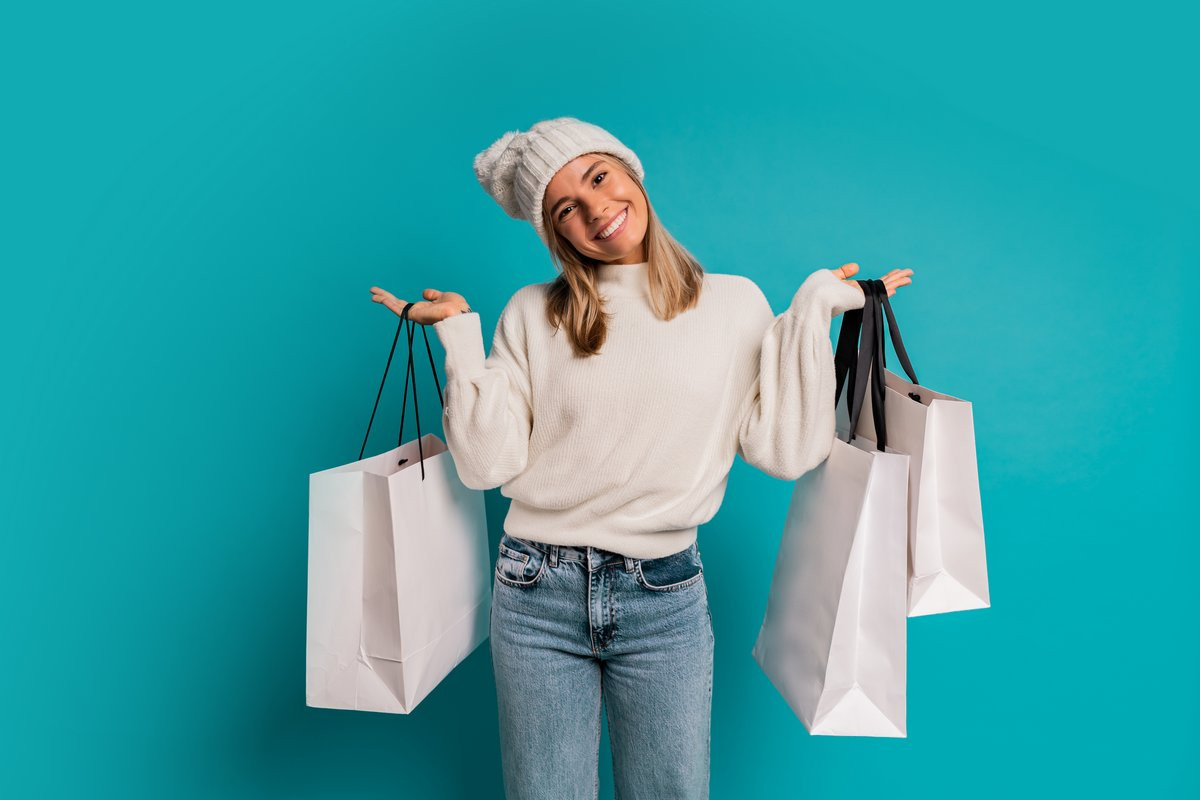 Femme à bonnet avec sacs de courses car les coupons de réduction de Rakuten sont là pour acheter smartphones pas cher