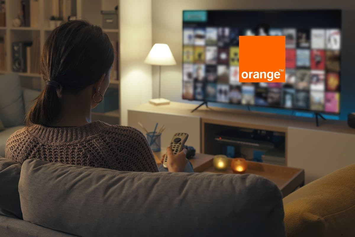 Femme dans son salon devant smart TV avec streaming et logo d'Orange car Apple TV+ dispo
