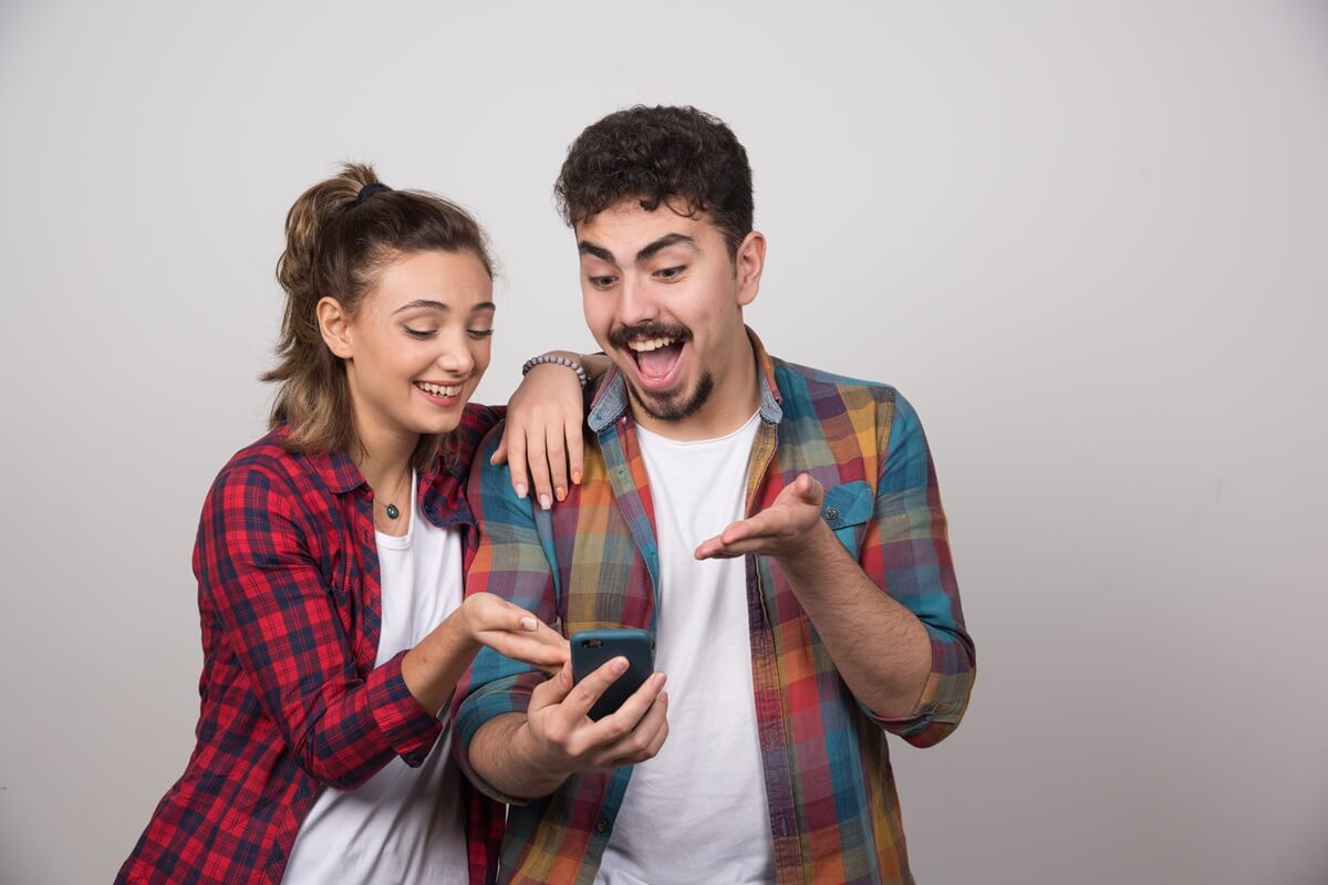 Homme et femme avec smartphones sourient, contents de leurs forfaits à moins de 5€ cgez RED by SFR